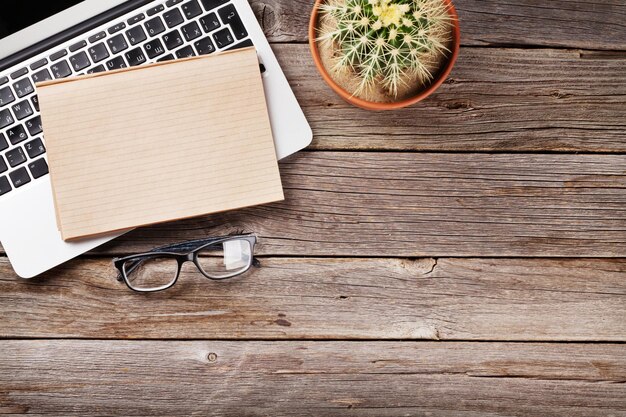 Desk table with laptop notepad and glasses