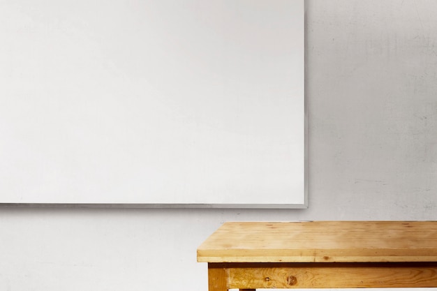 Desk and whiteboard inside the classroom with white wall background