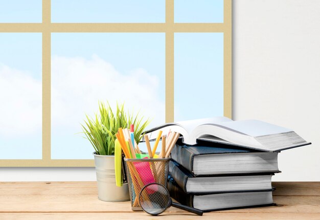 本と文房具のある机、窓ガラスの背景。学校に戻るコンセプト