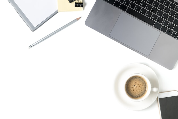 Desk with laptop, coffee, notebook and smart phone isolated on white background. Top view with copy 