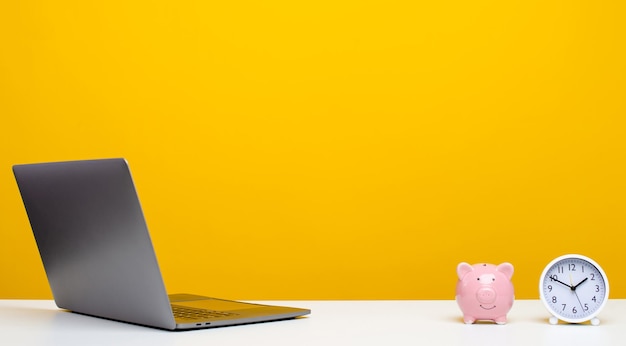 Desk with laptop with clock and piggy bank designer workspace with copy space