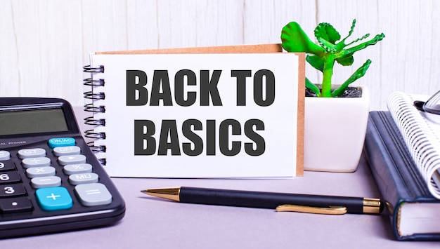 바탕 화면에는 계산기, 일기, 화분, 펜 및 BACK TO BASICS라는 텍스트가있는 노트북이 있습니다. 비즈니스 개념. 직장 가까이