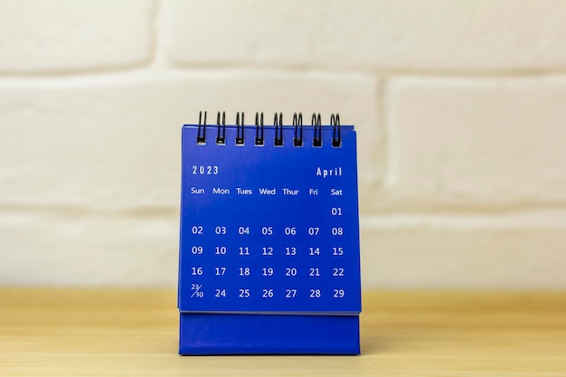 Desktop calendar for April 2023 on a wooden table