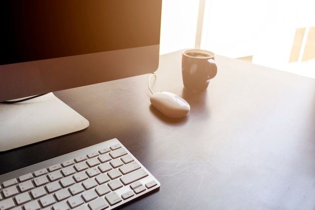 Desktop computer on black wooden table in office with soft-focus in the background