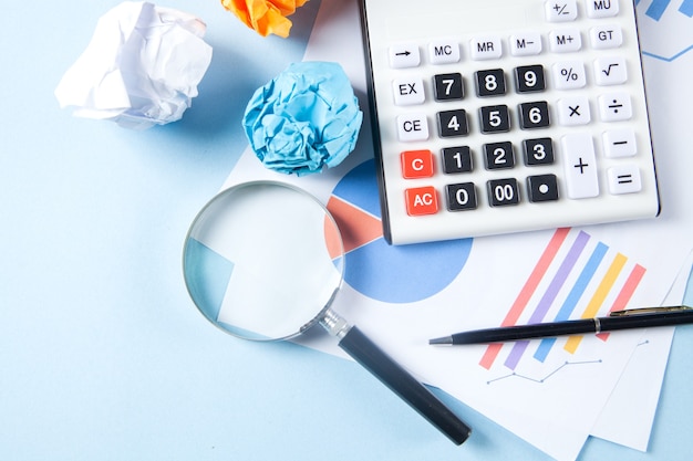 Desktop concept. statistics, calculator crumpled paper and magnifying glass on the table