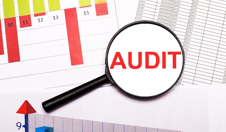 Photo on the desktop, graphs, reports, a magnifying glass with the inscription audit. business concept