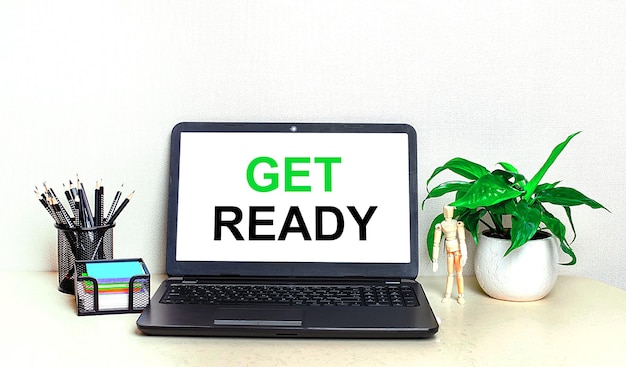 デスクトップには、鉢植えの植物の文房具と、画面に「GETREADY」というテキストが表示された開いたラップトップがあります。ホームオフィス