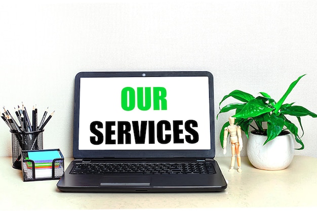 デスクトップには、鉢植えの文房具と、画面に「OUR SERVICES」というテキストが表示された開いたラップトップがあります。