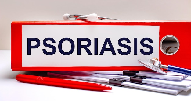 On the desktop is a stethoscope, documents, a pen, and a red file folder with the text PSORIASIS. Medical concept