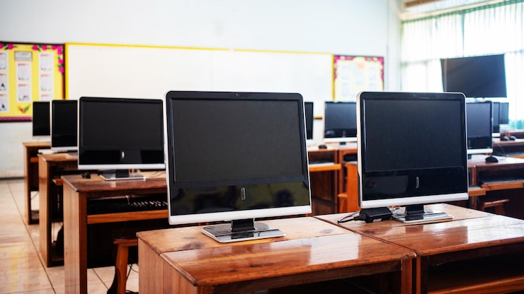 Photo desktop pcs on tables in classroom