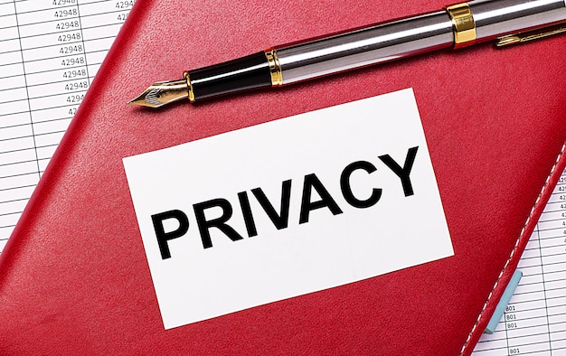 바탕 화면에는 PRIVACY Business 개념이라는 텍스트가 있는 부르고뉴 노트북, 만년필 및 흰색 빈 카드 보고서가 있습니다.