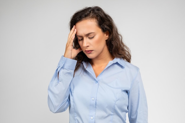 Despaired young european businesswoman with pained expression touch forehead