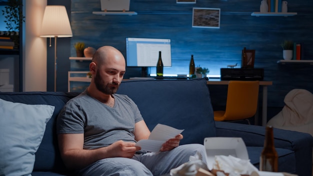 Desperate, depressed, helpless frustrated man reading paper letter with banking bills crying having notification, eviction notice. Shocked male by financial problems bankruptcy, unexpected bad news