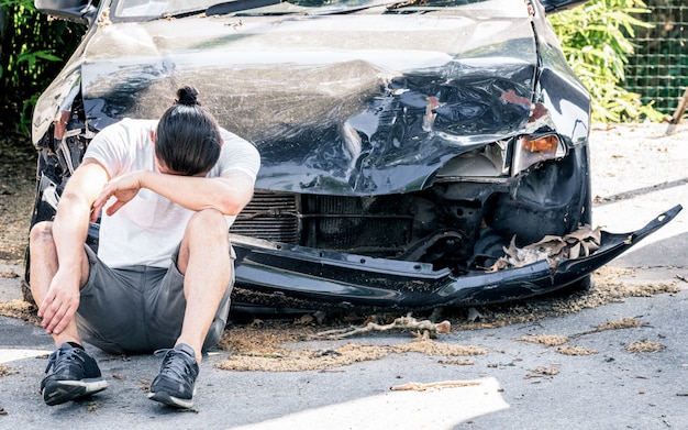 Desperate man crying at old damaged car after a crash accident