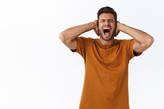 Desperate man screaming and covering his ears with his hands