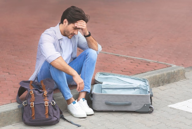 Desperate traveler sitting at international airport with empty suitcase