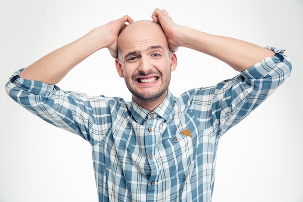 Photo desperate upset young man in plaid shirt with hands over head isolated on white wall