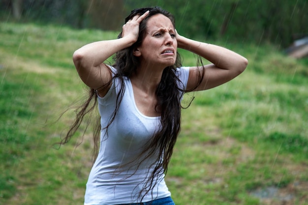 雨の中で泣きながら頭に手をかざす絶望的な女性と苦しめられた悪いニュース彼女の顔に悲しい表情長髪のブルネット悪天候コピーメンタルヘルスのためのスペース