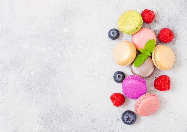 Dessert cake macaron or macaroon with raspberry and blueberry on stone kitchen . Top view.