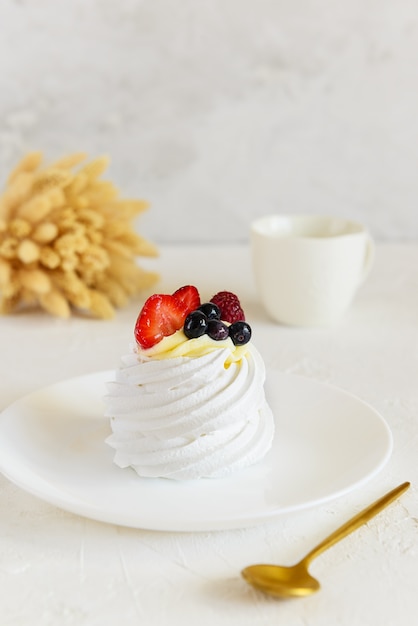 Dessert cake Pavlova with berries on a white plate.