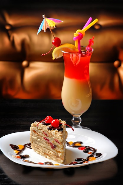 Dessert cake on a plate decorated with cherries on a cocktail table