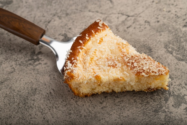 Dessert cake slices with coconut shavings placed on a stone table .