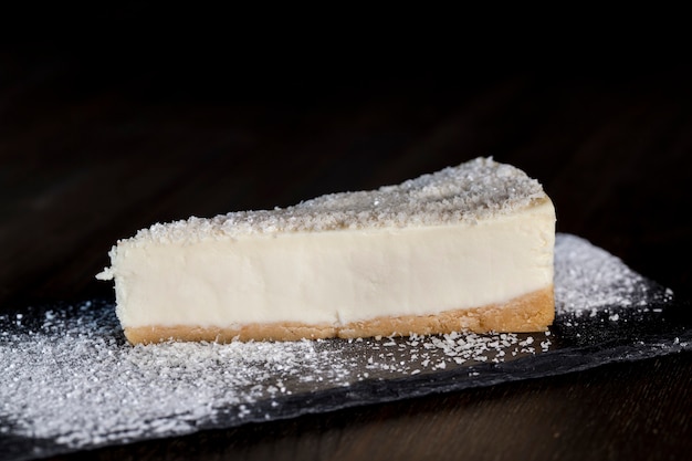 Dessert cheesecake bedekt met gedroogde kokospulp, cheesecake op een individueel dienblad bestrooid met poedersuiker