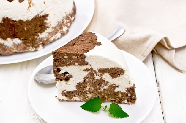 Десерт из творога и какао с желатином и сахаром в тарелке, кухонное полотенце на фоне светлой деревянной доски