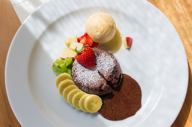 A dessert dish call chocolate lava include vanilla ice cream banana kiwi and apple