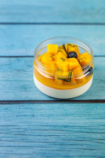 Dessert eigengemaakte pannacotta met mango op een blauwe houten achtergrond