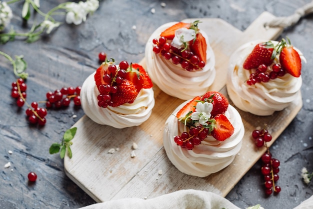 Dessert meringue with berries served on a wooden board