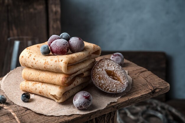 Dessert met pannenkoeken en bevroren kersen en lijsterbes op een sfeervolle vintage