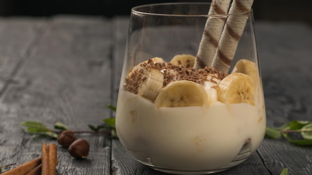 Dessert met plakjes banaan en wafelstokjes op een houten tafel