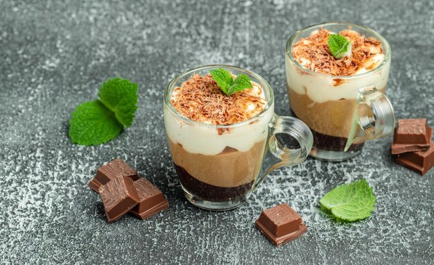 Dessert mousse three chocolates with mint on a dark background Layered delicious dessert Long banner format