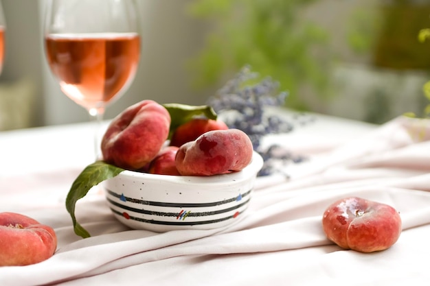 Dessert peaches and glass of wine on minimal white background