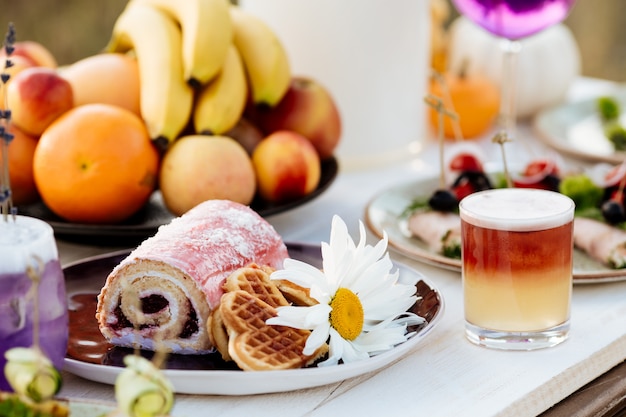 Dessert in a plate. Roll and cookies. Summer catering for the holiday on a white wooden table.