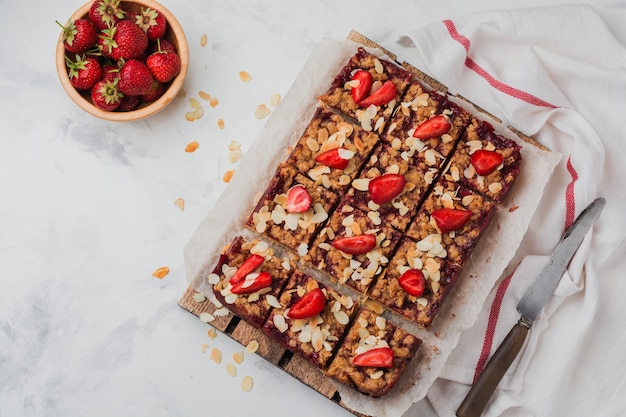 Dessert squares with strawberries and oat streisel on light concrete surface