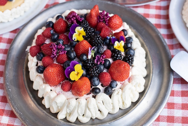 Dessert voor de vakantie zelfgemaakte cake met slagroombessen en eetbare bloemen