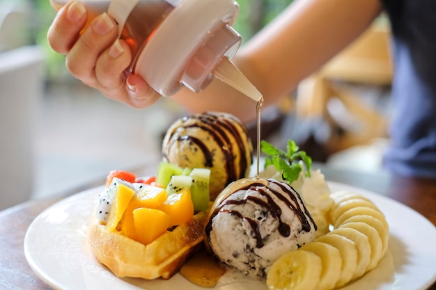  Dessert, waffles served with mixed fruits, sliced banana, ice-cream was pouring with honey