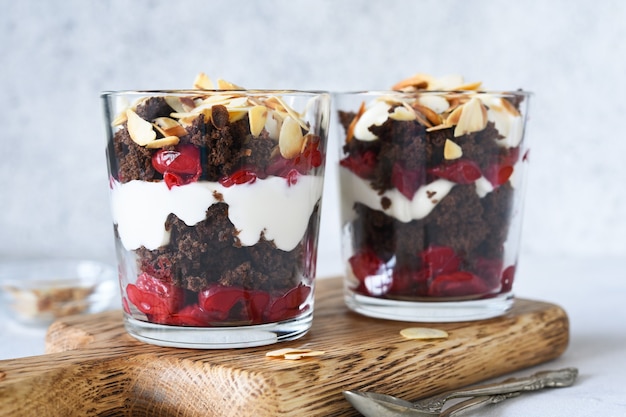 Dessert with cherries and a biscuit in a glass on a wooden board  