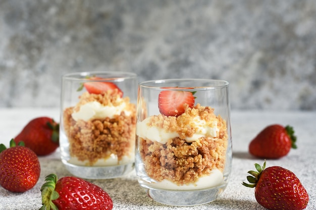 Dessert with crumbs, cream and strawberries. Cheesecake in a glass.