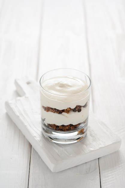 Dessert with mascarpone cheese and granola on a white wooden background