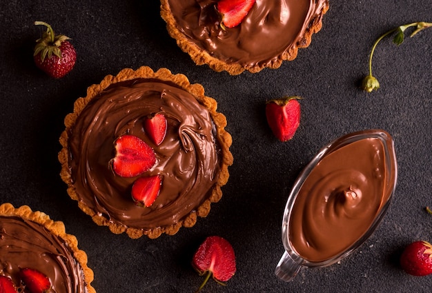 Foto dessert con burro di arachidi. crostata al cioccolato con fragole su fondo scuro