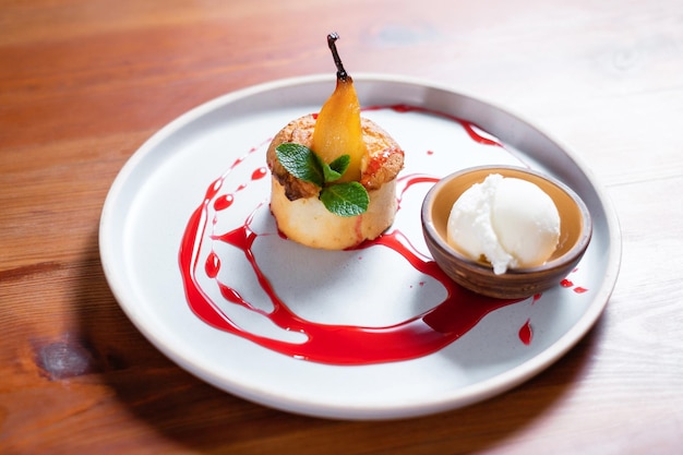 Dessert with pear and ice cream garnished with fruit sauce