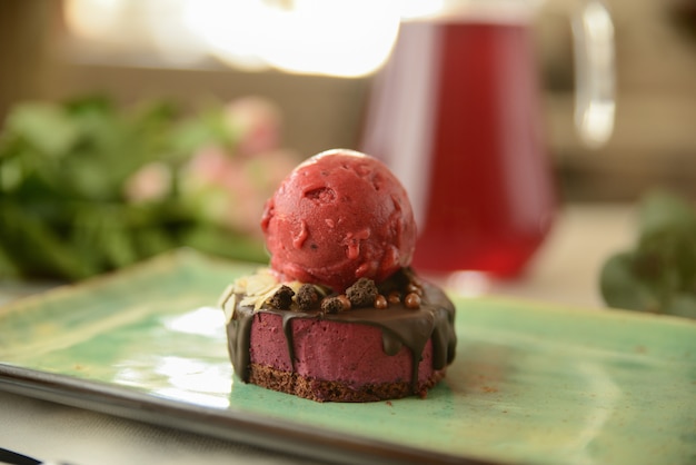 Dessert with a scoop of berry ice cream on a wooden table with flower decor