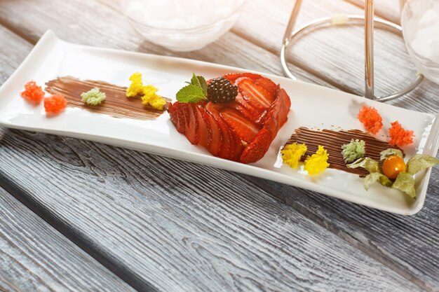 Dessert with strawberry and blackberry. Pieces of bread with berries. Tasty flan served at restaurant. Tasty high-calorie dish.