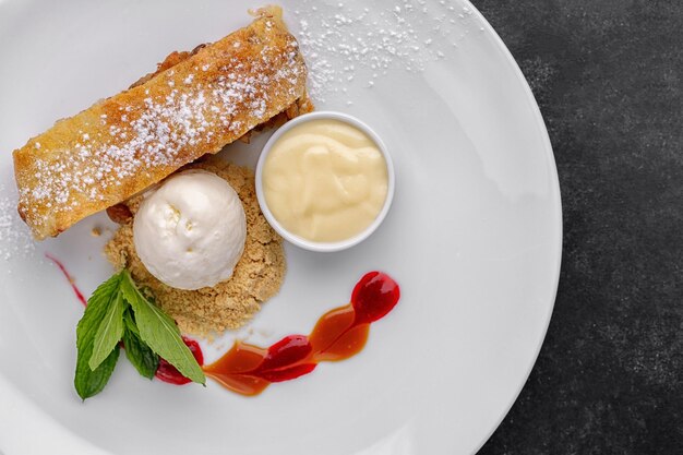 Dessertstrudel met appels en roomijs op een donkere achtergrond