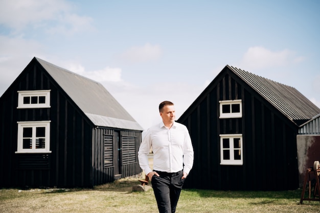 Destination iceland wedding a man in a white shirt walks between two wooden black houses