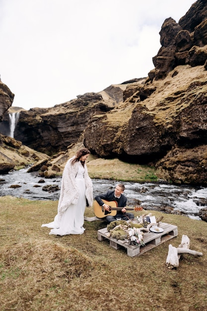 Destinazione islanda matrimonio vicino alla cascata di kvernufoss lo sposo suona la chitarra seduto sul