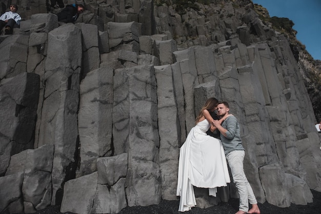 Destination iceland wedding. a wedding couple is walking along
the black beach of vic.